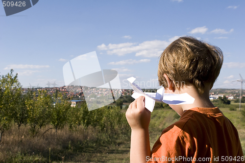 Image of young boy flying a paper plane