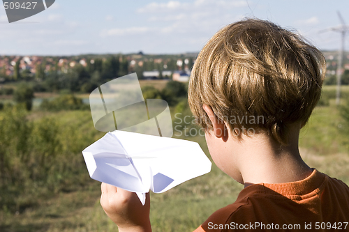 Image of young boy flying a paper plane