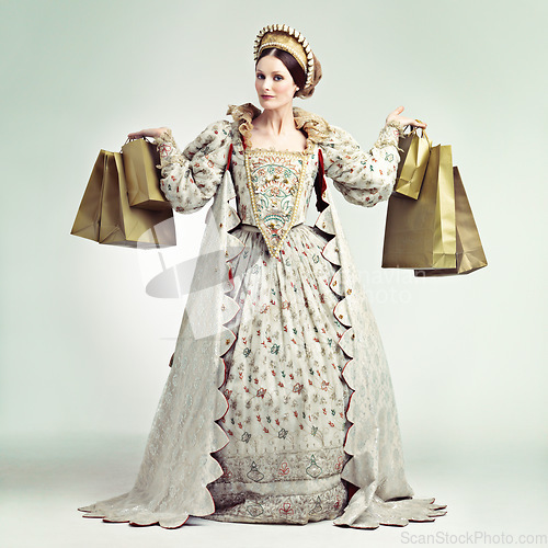 Image of Fashion, queen and portrait of woman with shopping bags in studio isolated on a gray background. Royalty, sales deals or rich and wealthy female ruler holding luxury golden gifts after buying at mall