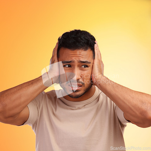 Image of Scared, loud and man worried by his stress and covering his ears in fear of noise isolated against a studio orange background. Young, hispanic or guy frustrated by sound causing head pain or ache