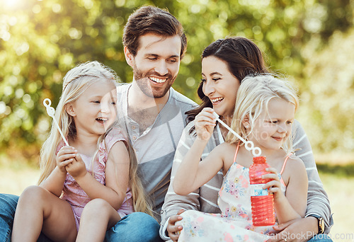 Image of Family, bubbles and park fun outdoor feeling happiness, love and parent care with children. Happy mom, dad and girl kids in nature on grass relax on vacation on summer holiday together with a smile