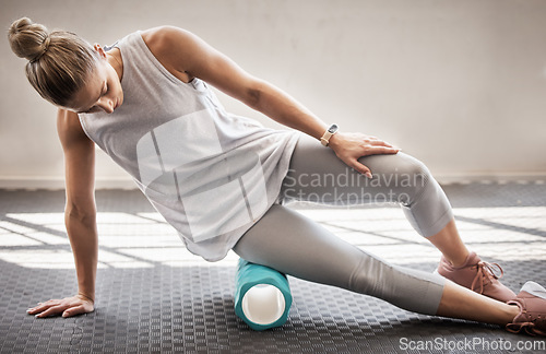 Image of Fitness, physio massage and woman with roller on floor for leg tension and support in yoga workout at gym. Health, pilates and massaging for sports physiotherapy, girl on ground foam rolling muscle.