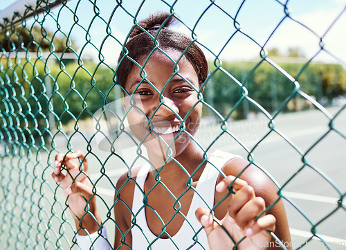 Image of Fitness, fence or portrait of black woman on a tennis court relaxing on training, exercise or workout break in summer. Happy, sports athlete or healthy African girl ready to play a fun match or game