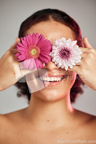 Image of Woman, face and flower eyes with smile for natural skincare, beauty or cosmetics isolated on a grey background. Happy female, person or lady smiling in happiness holding colorful plant petals for art