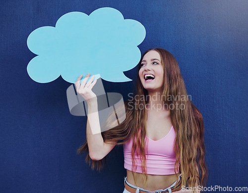 Image of Happy woman holding a speech bubble with mockup space standing by a blue wall with a sign. Gen z, happiness and young female with a chat board with mock up or copy space for marketing or advertising.