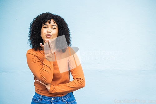 Image of Portrait, kiss and woman flirting in studio for fun, playful and personality against a blue background. Black woman, blowing kiss and emoji for kissing, attraction and desire while standing isolated