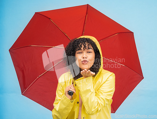 Image of Woman, portrait or blowing kiss and rain umbrella on isolated blue background in Brazil city love or support. Black person, raincoat or flirty student and facial expression or water weather insurance