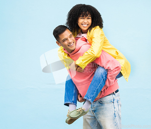 Image of Happy couple, bonding or piggyback on isolated blue background in city travel, date or fun game. Smile, happy or man carrying black woman in silly, goofy or playful activity in trust, support or love