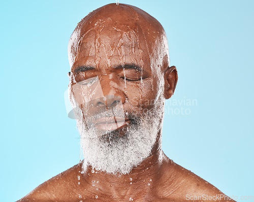 Image of Shower, black man and water for cleaning, skincare and wellness on blue studio background. Mature male, elderly guy and face wet for hygiene, washing or body care for beauty, cosmetics or clear skin