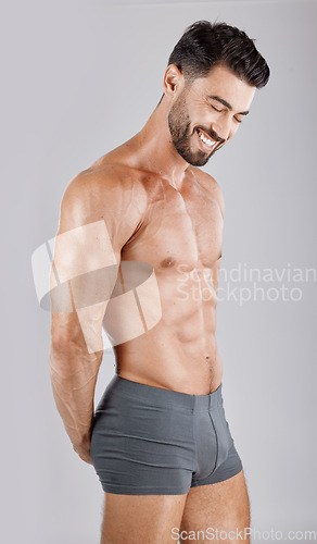 Image of Fitness, body and man in underwear in a studio for health, wellness and exercise for muscle. Happy, smile and muscular male model from Puerto Rico isolated by a gray background after a workout.