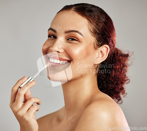 Image of Woman, smile portrait and apply lipstick for beauty, cosmetics dermatology and skincare wellness in grey background. Female model, face and makeup application or lip balm product for happy self care