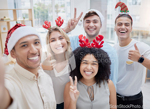 Image of Christmas party, selfie and business people with hand gesture taking pictures. Xmas portrait, employee or group of friends taking social media photo with thumbs up or peace sign at office celebration