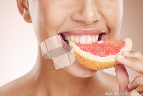 Image of Diet, nutrition and woman eating grapefruit for skincare, beauty glow and vegan detox on a studio background. Vitamin c, health and mouth of a model advertising a fruit for care of body and skin