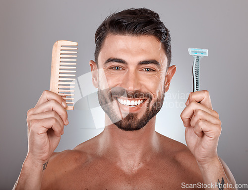 Image of Portrait, shaving and comb with a man model holding a razor in studio on a gray background for skincare. Face, wellness and hands with a handsome young male in the bathroom to shave his beard