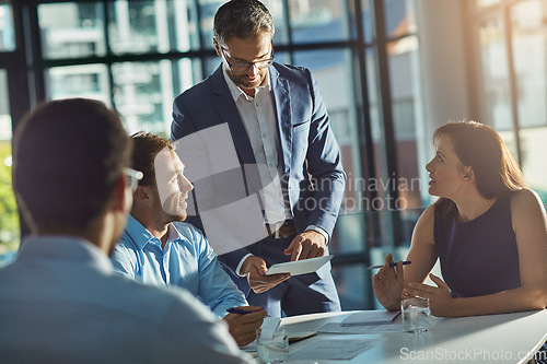 Image of Man, tablet and business people in meeting for planning, goals and mission at desk with diversity. Teamwork, mobile tech and leadership for vision, collaboration and innovation in financial company