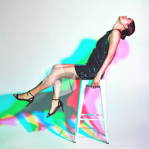 Image of Fashion, chair and woman model in studio with neon color lights or shadow isolated on a white background. Young model person with kaleidoscope style, glitter dress and psychedelic mockup copy space
