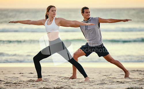 Image of Warrior pose, couple and beach yoga at sunset for health, fitness and wellness. Exercise, zen chakra and man and woman stretching, training and practicing pilates for balance outdoors at seashore.