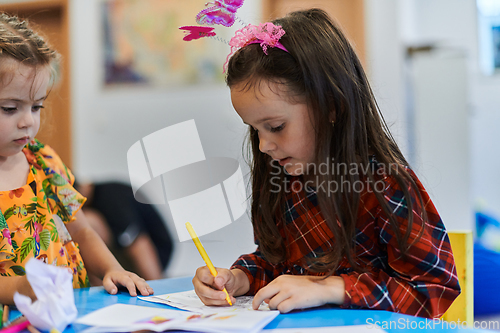 Image of Creative kids sitting in a preschool institution, draw and have fun while they get an education