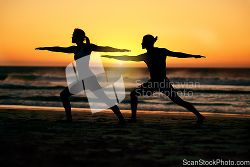 Image of Couple, silhouette and beach yoga at sunset for health, fitness and wellness. Warrior pose, zen chakra and man and woman stretching, training and practicing pilates for balance outdoors at seashore.