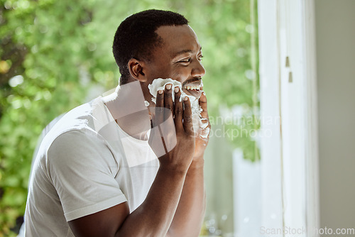 Image of Beard, cream and shaving black man in the morning, beauty grooming and hair removal in a home bathroom. Skincare, cosmetic and happy African person applying foam to face for clean facial hair shave