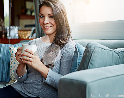 Image of Coffee, woman and portrait of a person at home on a living room sofa with a smile in the morning. Drink, happy person and lens flare on a lounge house couch with tea feeling happiness in a room