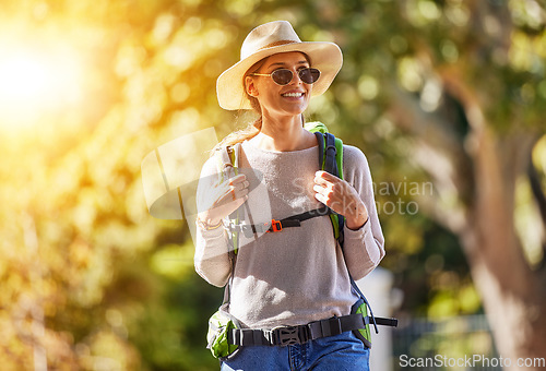 Image of Nature, adventure and woman hiking in a forest for outdoor exercise, wellness and fresh air. Happy, smile and female trekking or walking in a green garden with a backpack and sunglasses in Canada.