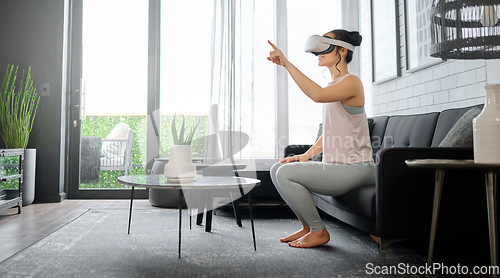 Image of VR, metaverse and gaming with a woman in the living room of her home using a headset to access a 3d game. Futuristic, virtual reality and technology with a female gamer using ai to play games