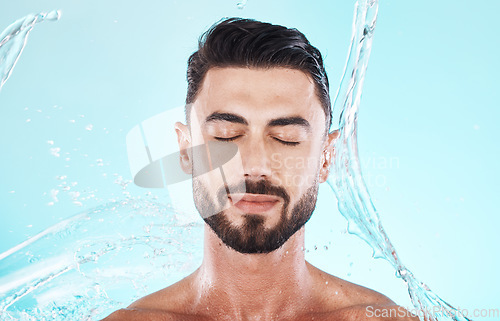 Image of Water, splash and skincare with face of man for shower, self care and natural cosmetics. Luxury, hydration and refreshing with model for dermatology, wellness and cleaning in blue background studio