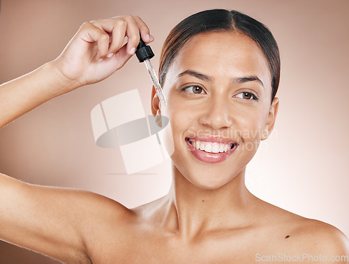 Image of Skincare, beauty and woman with a face serum for a natural, wellness and cosmetic face routine in a studio. Health, glow and female model from Brazil with a facial oil isolated by a brown background.