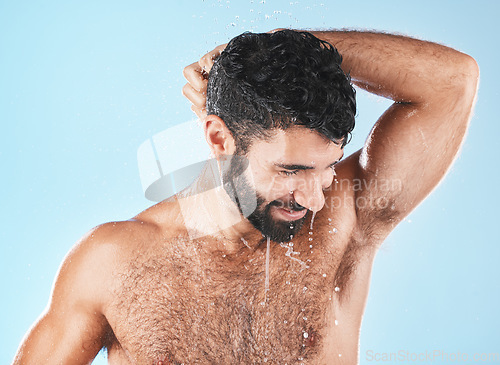 Image of Water, shower and a man washing hair with shampoo in studio on a blue background for beauty or hygiene. Hair, cleaning or treatment with a handsome male wet in the bathroom while bathing for haircare