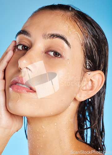 Image of Portrait, water and woman cleaning, skincare and dermatology for health, wellness and on blue studio background. Face, lady and female with hygiene, wet and shower for natural beauty and cosmetics