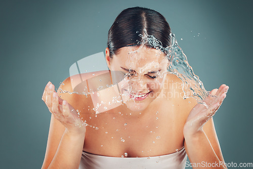 Image of Skincare, face and water splash on woman cleaning skin for hygiene and hydration isolated in a studio background. Self care, dermatology and young female washing or grooming for adult beauty