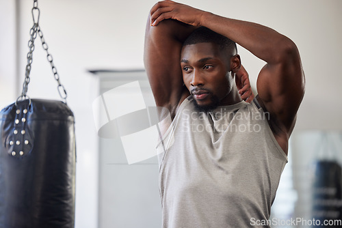 Image of Black man stretching, boxing gym and training for fitness, wellness or focus for strong body. Man, punching bag and warm up muscle with vision, goal or development in workout, mma exercise or health