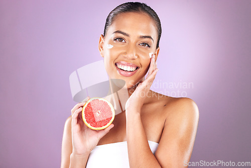 Image of Woman, face skincare or grapefruit product on purple studio background for organic dermatology, healthcare wellness or self care grooming. Portrait, smile or happy beauty model and fruit facial cream