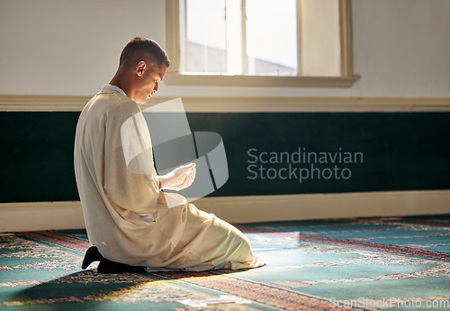 Image of Mosque, worship and muslim man in prayer on his knees for gratitude, support or ramadan for spiritual wellness. Religion, tradition and islamic guy praying or reciting quran to allah at islam temple.