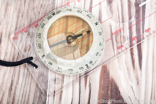 Image of Transparent plastic compass on wooden background