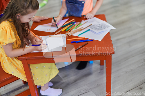 Image of Close up photo of kids during an art class in a daycare center or elementary school classroom drawing with female teacher.