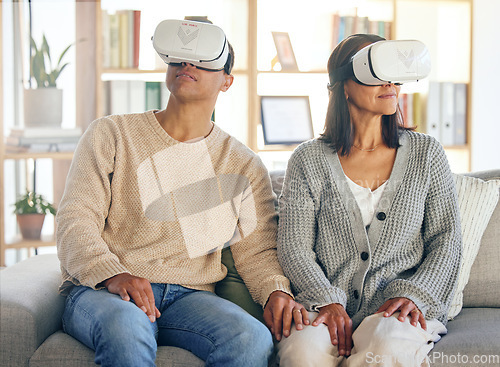 Image of Virtual reality, 3d and a couple in the interactive metaverse while together on a sofa in the living room of a home. VR, goggles and gaming with a man and woman in their house to relax or video game