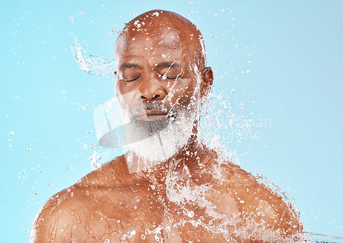 Image of Senior black man, water splash and skincare in studio for wellness, clean or health facial by backdrop. Man, model face and water on skin, healthy self care or anti-aging beauty by blue background