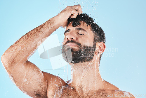 Image of Water, shower and a man washing hair with shampoo in studio on a blue background for beauty or hygiene. Hair, cleaning and bathroom with a handsome male wet in the bathroom while bathing for haircare