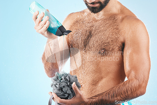 Image of Shower gel, body care and man in a studio for skin hygiene, health and wellness after a shower. Soap, morning routine and male model cleaning or washing his wet body with a sponge by blue background.