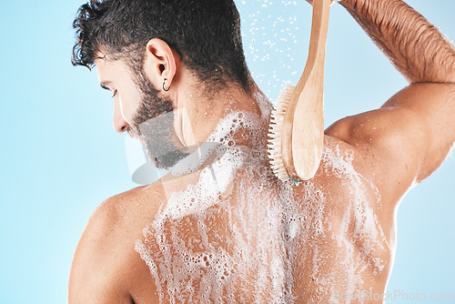 Image of Back, man and shower with foam, skincare and cleaning for body care, wellness and against blue studio background. Male, guy and washing with water, beauty and cosmetics for grooming, bare and fresh