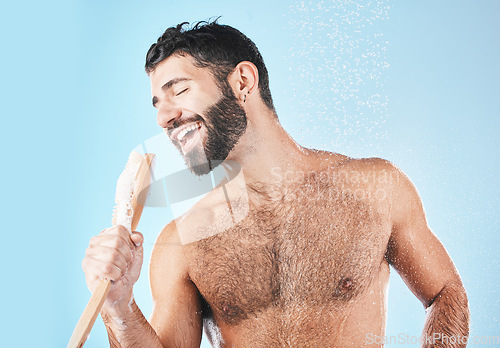 Image of Shower, singing and cleaning with a man model in studio on a blue background using a loofah to sing. Water, bathroom and hygiene with a handsome male wet while washing for personal body care