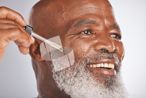 Image of Skincare, wellness and man with a face serum in a studio for a healthy, cosmetic and natural routine. Beauty, cosmetics and African male with a facial oil treatment isolated by a gray background.