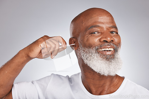 Image of Cotton bud, cleaning ear and senior black man happiness portrait for grooming hygiene, self care and cosmetics earwax removal in white studio background. Elderly african model, smile and ears cleaner