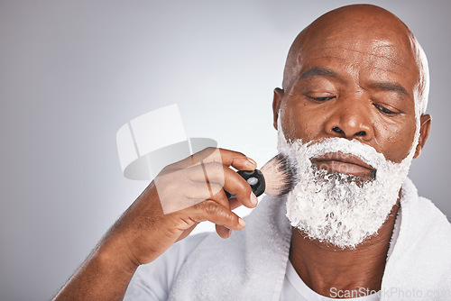 Image of Face, shaving cream and black man with brush on beard, skincare spa treatment on grey background. Health, mock up and facial hair, mature man morning shave routine with space for product placement.