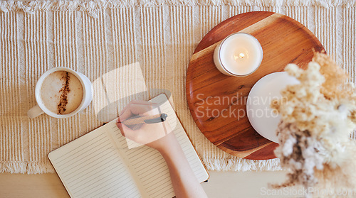 Image of Coffee, hand and writing in journal top view with candle for calm, peace and relax morning routine. Woman, notebook and diary planning goals, lifestyle motivation or creative writer with warm drink