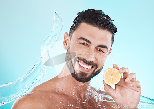 Image of Beauty, skincare and man with a lemon and water splash for dermatology, facial wellness and nutrition on a blue background in studio. Fruit, diet and face portrait of a model with vitamin c for body