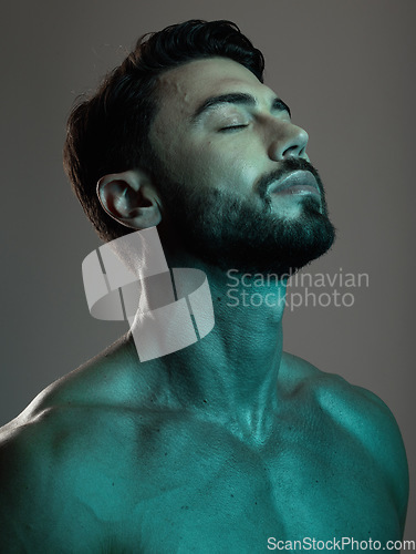 Image of Man, face and neon with beauty and skincare, grooming and wellness with eyes closed against studio background. Healthy skin, relax in blue light and peace, self care and cosmetic facial and treatment