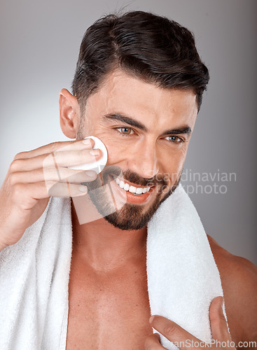 Image of Cosmetics, skincare and man with cotton pad, natural beauty and on grey studio background. Male, guy and makeup with cottonwool, treatment and routine with smile, towel and healthy for luxury and spa